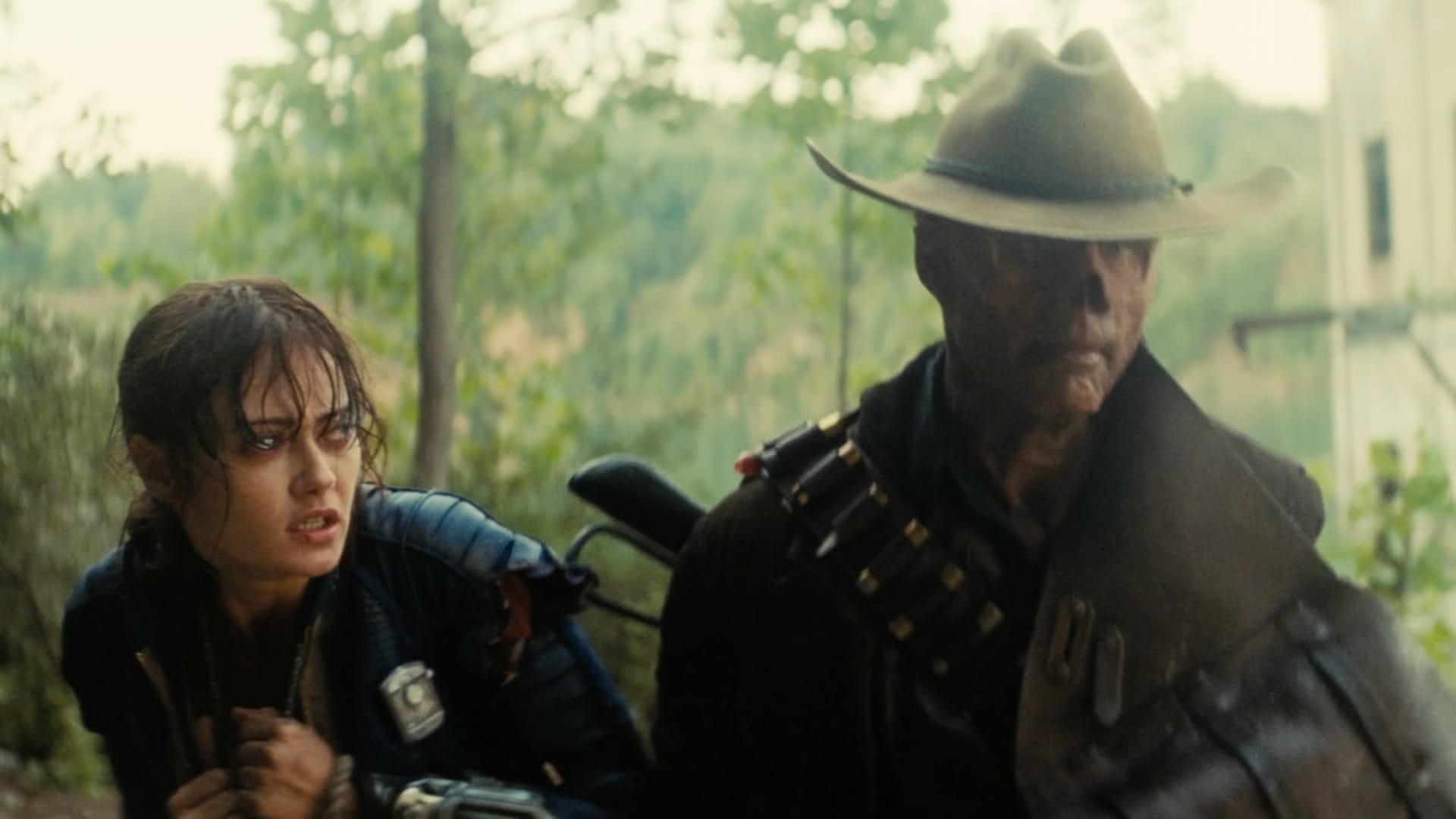 Lucy, wet and cold, looks incredulously at The Ghoul (wearing leather, a bandolier, a cowboy hat, and having no nose)