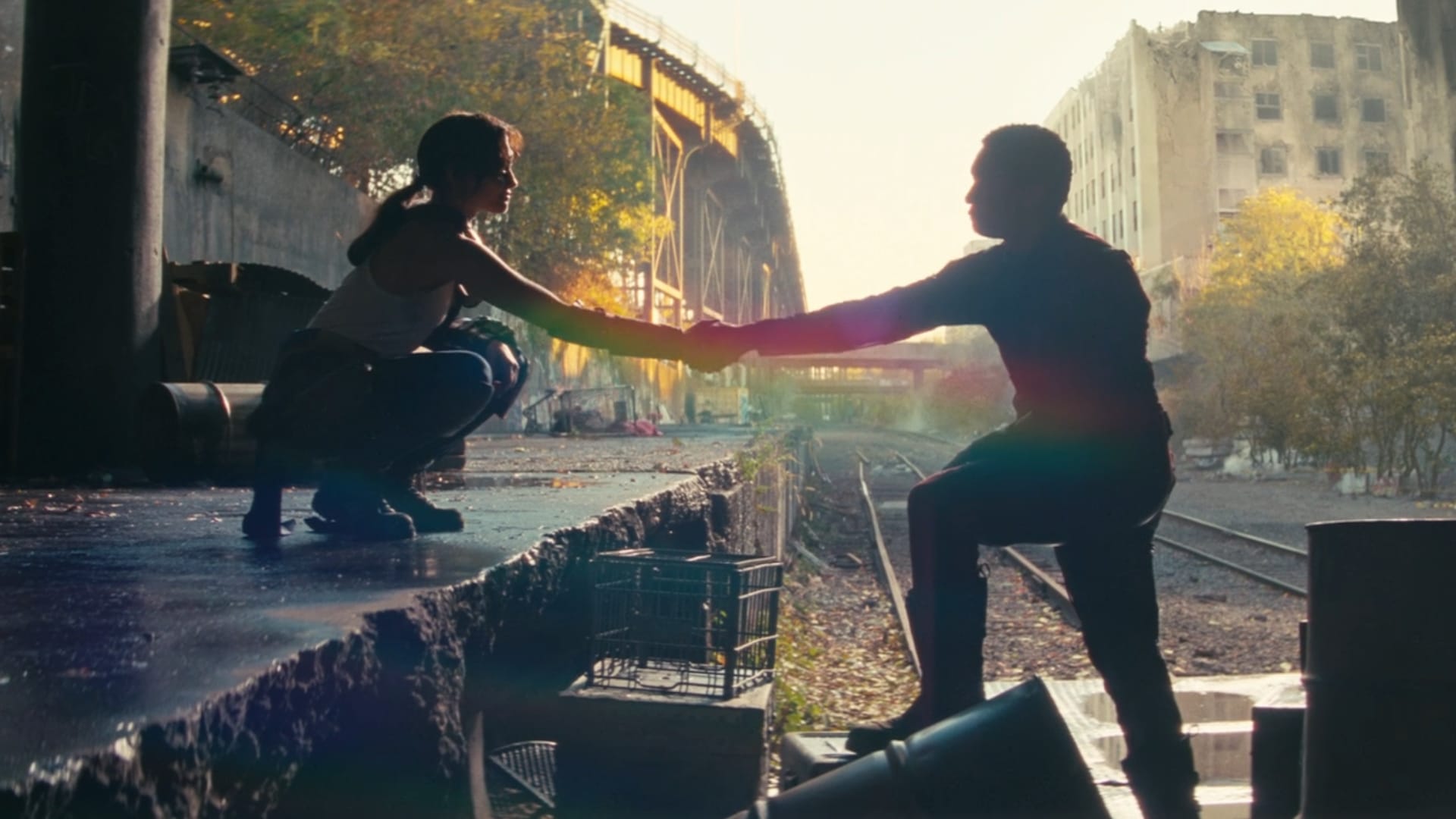Lucy, wearing her tank top, clasps hands with Maximus as she crouches on a platform and he stands with one leg raised on a crate. A rainbow lens flare appears behind their hands.
